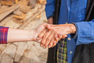 Hand einer alten Frau in der Hand einer jungen Frau