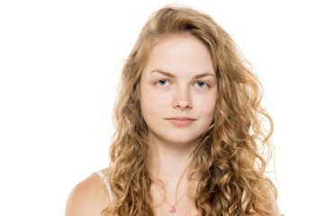 Young woman with curly blonde hair, freckles and natural makeup, looking at camera. Close-up...