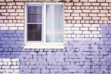A brick wall with a window and a fire hydrant.