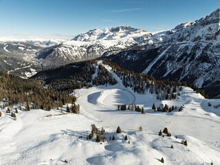 Aerial drone view of sunny winter in dolomites, alps. Pinzolo village and a ski resort in Italy. Dolomites Brenta, Adamello park and Presanella moutain, Doss del Sabion skiarea trentino Italy.