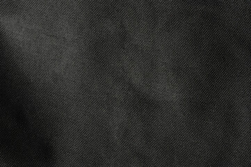 Textured black fabric displaying subtle patterns and depth in soft light