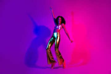 Young woman dancing in vibrant neon lighting, wearing glamorous retro fashion with metallic gold pants, expressing joy and positivity
