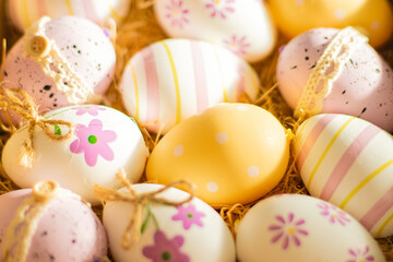 Close-up of colorful Easter eggs in a basket with natural straw, perfect for Easter celebrations and festive decorations.