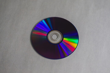 A close-up of a compact disc with rainbow stripes on a gray background. 