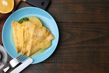 Plate with tasty crepes Suzette served on wooden table, flat lay. Space for text