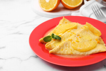 Plate with tasty crepes Suzette on white marble table, closeup. Space for text
