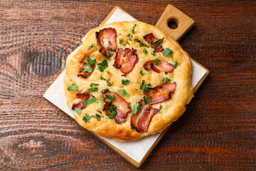 Delicious focaccia bread with bacon and parsley on wooden table, top view