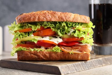 Delicious baguette sandwich with tomatoes and yellow beans on grey textured table, closeup