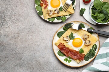 Delicious crepes with eggs, bacon and mushrooms served on grey table, flat lay. Space for text
