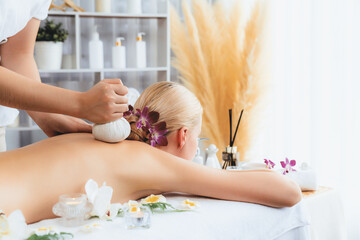 Hot herbal ball spa massage body treatment, masseur gently compresses herb bag on woman body....