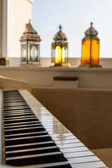 A piano keyboard with coloured lanterns in the background. Serene musical concept. Selective focus on the nearest keys.