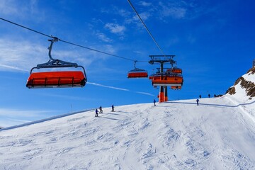 A stunning view of a group of vibrant orange ski lifts ascending a snow-covered mountainside, with...
