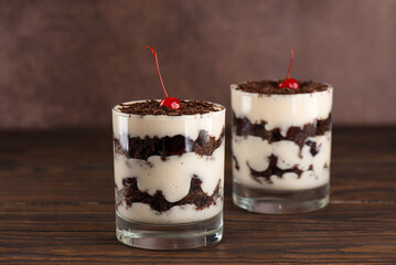 Cherry, vegan cream with shea butter and chocolate biscuit layered dessert in glasses. Black forest or Schwarzwald trifle.