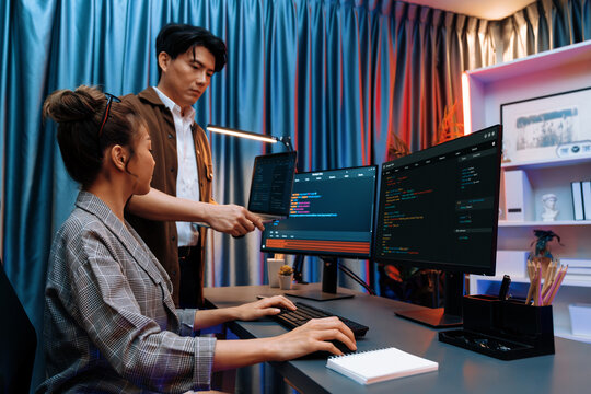 Serious of IT developers discussing intelligent website development coder system running data online two screens with laptop showing information network at neon light room at modern office. Infobahn.