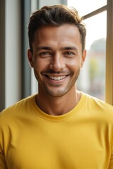Obraz premium smiling man in yellow shirt looking at camera with open window