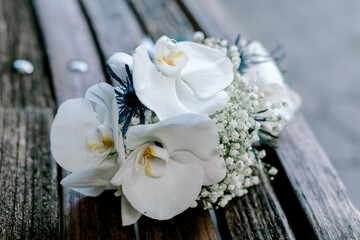 Elegant white orchid and baby’s breath bouquet resting on a wooden surface in natural light