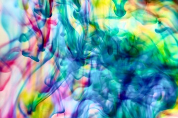 Abstract video with vibrant colors flowing with colored inks dispersed in water. The composition consists of shades of blue, red, green and yellow blending and swirling on a light background, creating