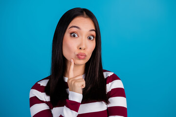 Pensive young woman making a thinking gesture against blue background