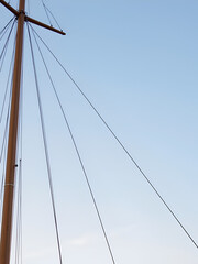 Sailing ship mast with rigging and cables against the sky.