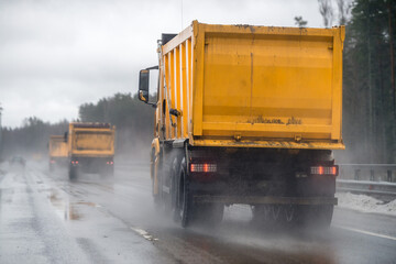 A yellow truck is driving along the highway. Road construction equipment.