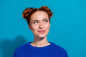 Young woman with trendy hairstyle smiling in front of bright blue background, wearing a casual...
