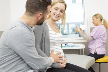 Obraz premium doctor and future parents smiling in medical office