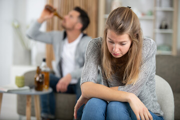 man pouring alcohol and woman sitting upset