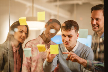 Diverse group of businesspeople brainstorming with sticky notes on a glass wall