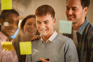 Diverse group of businesspeople brainstorming with sticky notes on a glass wall