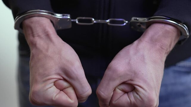 Male Hands Restrained in Steel Cuffs