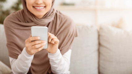 Modern Communication. Closeup Of Unrecognizable Muslim Woman In Hijab Using Smartphone At Home, Browsing Internet Or Texting With Friends, Panorama