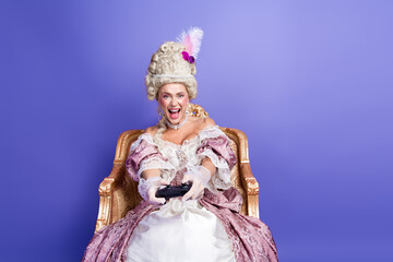 Fototapeta premium Elegant woman in vintage royal costume enjoying entertainment with a gaming controller