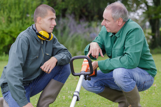 young gardener being shown how to operate a strimmer