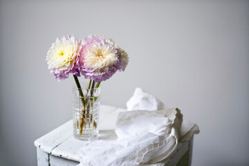 A bouquet of three white dahlias with pink-edged petals on a stool with a napkin. Space for text.