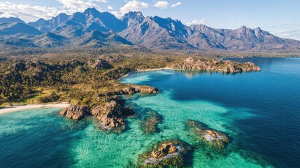 Obraz premium Aerial view of pristine beach, turquoise water, mountains, and lush foliage