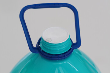 Close-up. Large, sealed turquoise bottle with a white cap and a blue handle.
