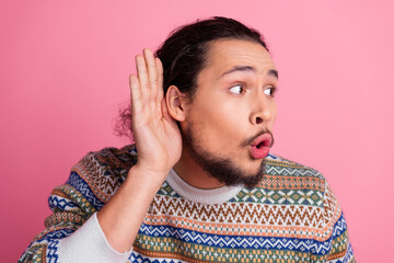 Charming Young Man Listening with Hand Gesture Against Pink Background
