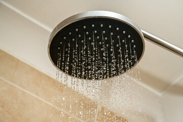Increasing water bills. Chrome shower head with water droplets.