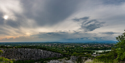 ampia composizione panoramica con vista sul territorio in pianura nell'area nord-est della regione Friuli Venezia Giulia, al tramonto, all'arrivo di un temporale estivo