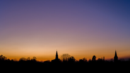 Fototapeta premium sunset at the blue hour with the skyline of the two churches of ratingen homberg with colored sky 
