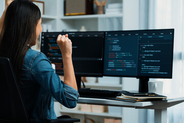 Young Asian IT developer creating raising fist up with successful information on pc with coding...