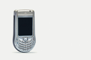 Vintage silver mobile phone with worn body on white background