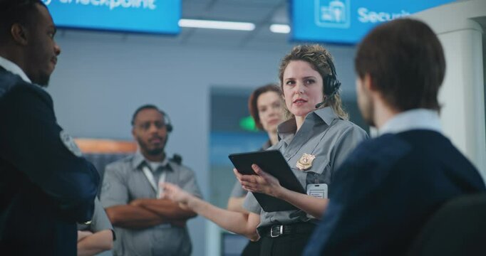 Airport Security System: Female TSA Officer with Tablet Computer Wearing Headset Instructs Airport Staff at Checkpoint About Scanning Process of Passengers, Screening Procedures for Boarding Flight.