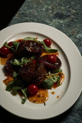 a red meat steak with vegetables on a white plate