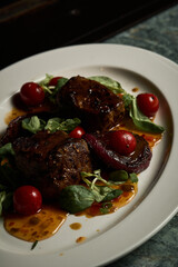 a red meat steal with vegetables on a white plate