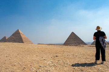 Young Woman looking at Giza Necropolis, Famed archaeological site featuring the Great Pyramids, the Great Sphinx and The Great Pyramid of Giza in the desert of Giza, Cairo, Egypt.