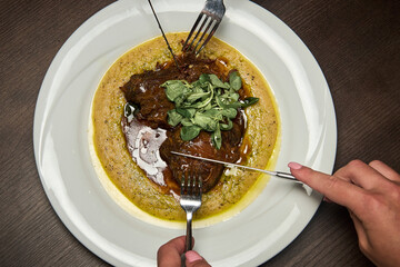a red meat steak with mashed potatoes on a white plate