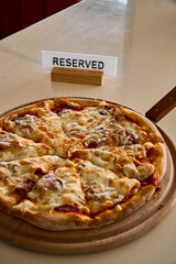 a cheese pizza on a wooden board on a white table