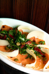 vegetable salad with prosciutto and pear on a white plate 