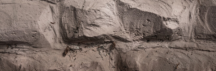 Masonry texture. The rough surface of the stones is plastered and painted. Wide panoramic texture for background and design.